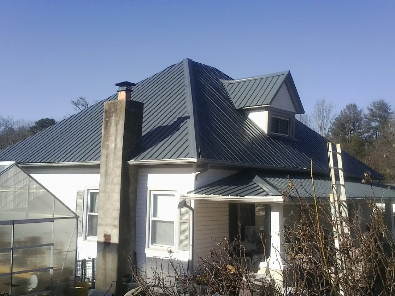 Dark blue standing seam metal roof on a white farmhouse with dormer — Slate & Tile Roof Repair by Roofing Brothers in Denair