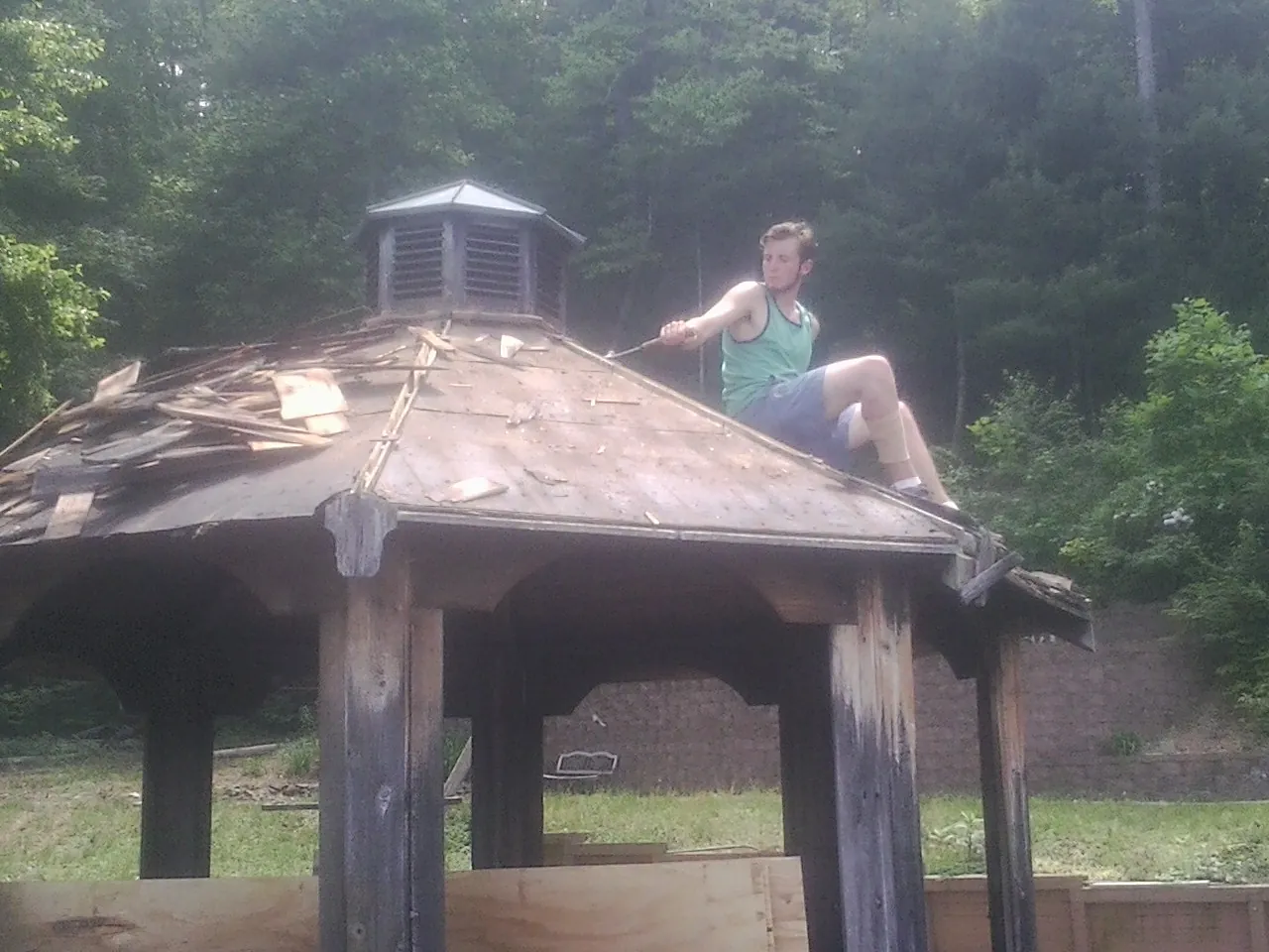 Tearing the old roof off a wooden gazebo before new shakes in Denair