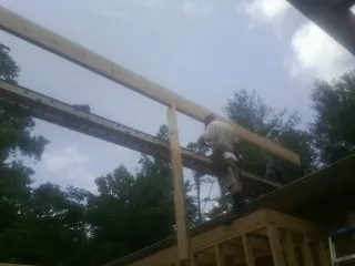 Carpenter setting a ridge beam over a new addition frame — Ice Dam Removal by Roofing Brothers in Denair