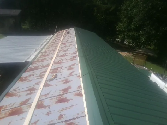 Old rusted panels beside newly installed green metal roofing — Wind Damage Roof Repair by Roofing Brothers in Denair