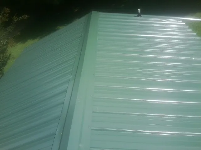 New green metal panels meeting at the ridge of a roof — Flat Roof Repair work by our crew in Denair
