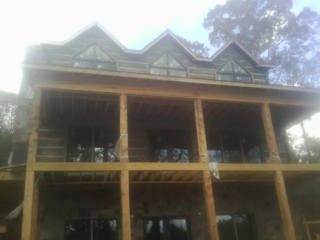 Dormers and porch framing on a large log home under construction — Roof Coating work by our crew in Denair