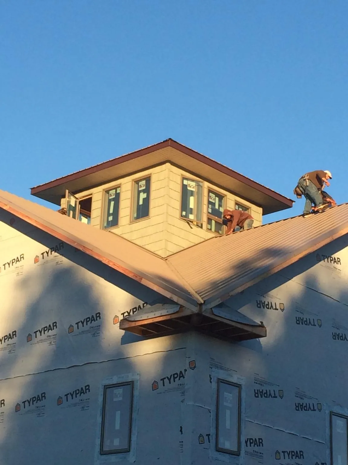Roofers working around a rooftop cupola on a new metal roof at sunset — Roof Waterproofing in Denair by Roofing Brothers